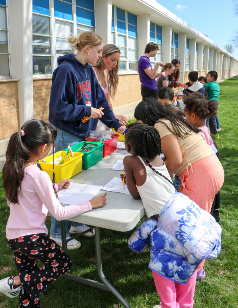 Children and volunteers doing outdoor coloring activities.